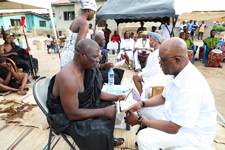 Ghanaian Men and Women leading a traditional ceremony with tourists